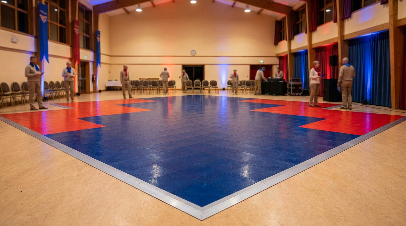 Piste de danse modulaire bleue et rouge installée au centre d'une salle des fêtes municipale avec des personnes autour.